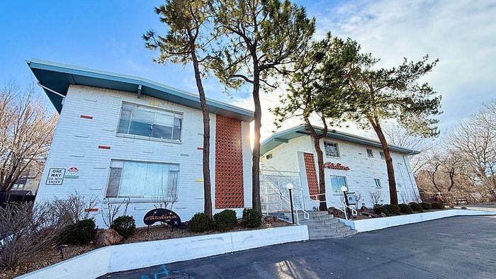 Charming apartment complex with retro architecture, surrounded by lush trees and well-maintained landscaping.