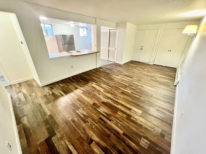 Charming open-plan living space with sleek wooden floors and a cozy kitchen view.