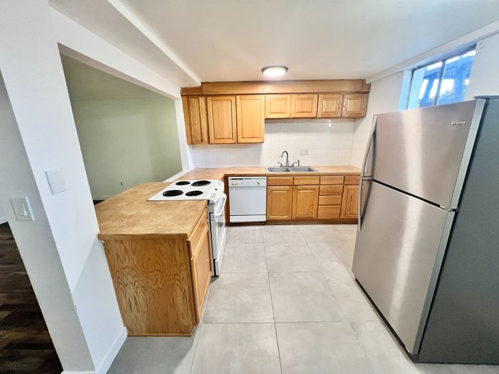 Inviting modern kitchen with sleek stainless steel appliances, wooden cabinetry, and elegant tile flooring, perfect for culinary creativity.