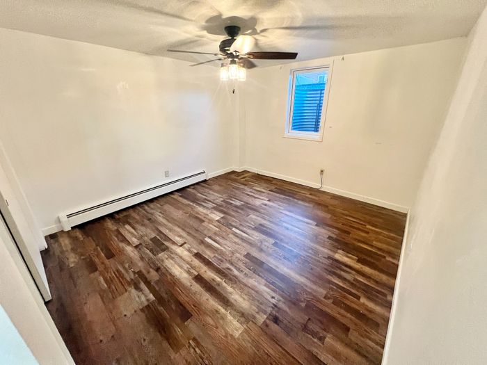 Charming room with polished hardwood floors, modern ceiling fan, and natural light streaming through a window.