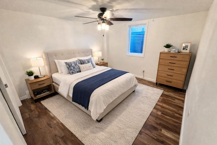 Inviting bedroom with cozy bed, elegant d&eacute;cor, and warm lighting on hardwood floors.