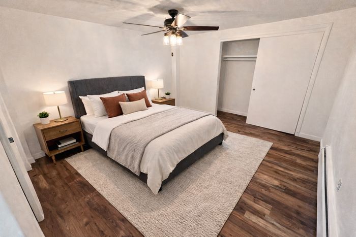 Inviting modern bedroom with a luxurious bed, wooden floors, and elegant lighting, perfect for relaxation.