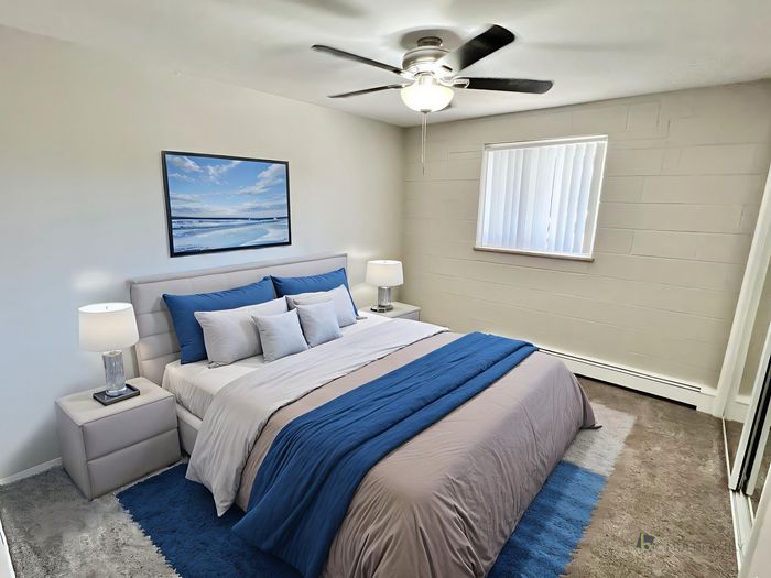 Inviting bedroom with stylish blue accents, modern decor, and a serene wall painting, perfect for relaxation.