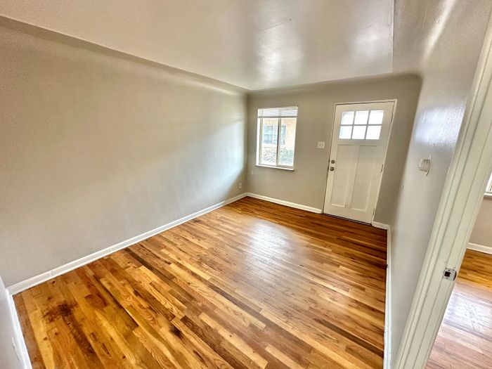 Inviting living room with rich hardwood floors and abundant natural light from large windows.