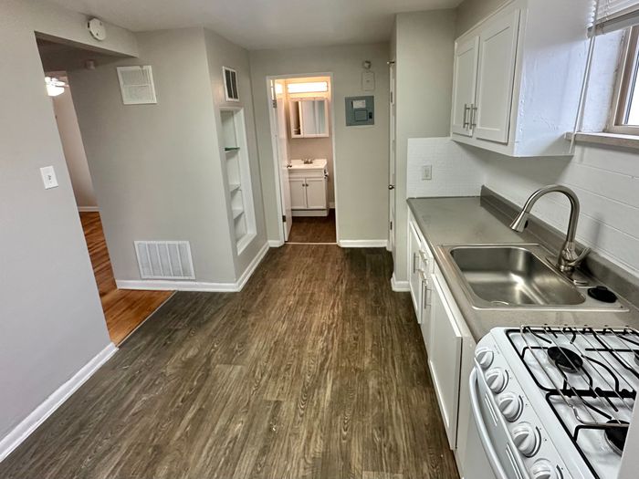 Modern kitchen with sleek countertops, stainless steel sink, and elegant cabinetry opening to a cozy bathroom.