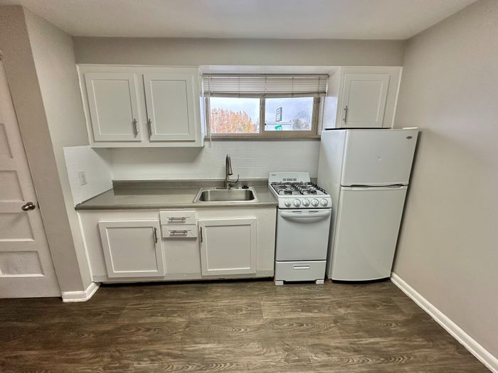 Charming compact kitchen with modern white cabinetry, sleek countertops, and a cozy stove, perfect for city living.