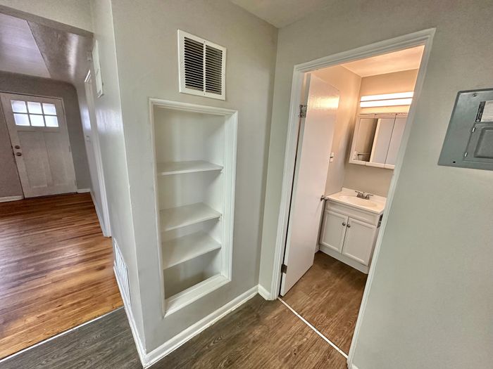 Charming entryway with built-in shelving, gleaming hardwood floors, and a cozy bathroom. Ideal for modern living.