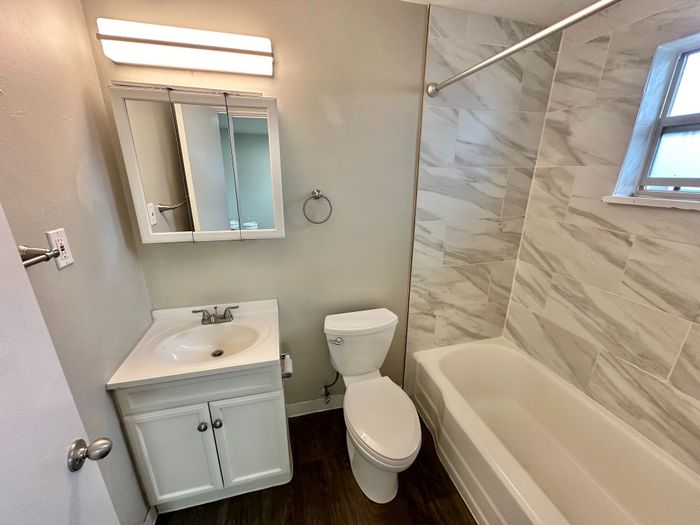 Charming bathroom with elegant marble tiles and a sleek vanity mirror, offering modern comfort and style.