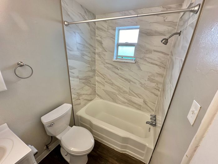 Modern bathroom featuring elegant marble tile walls and a sleek bathtub with a window view.