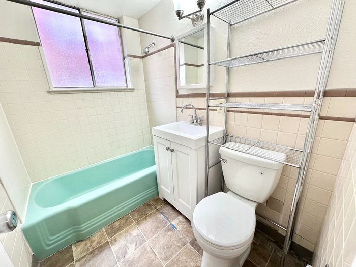 Bright and charming bathroom with a vintage green bathtub, modern sink, and stylish shelving unit.