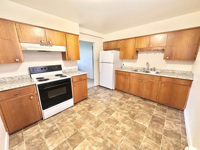 Charming kitchen with vintage wooden cabinets, granite countertops, and modern appliances in a cozy apartment.