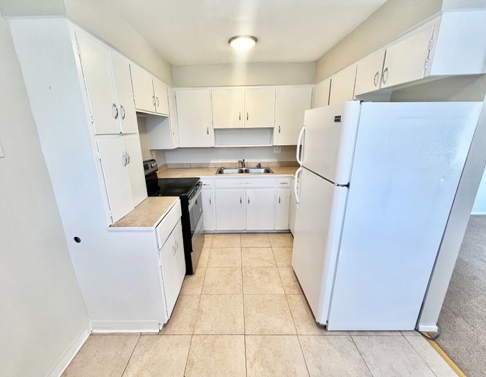 Bright, spacious kitchen with modern white cabinetry, sleek countertops, and large appliances, perfect for culinary enthusiasts.