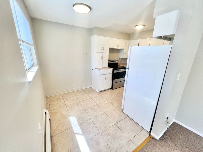 Bright and airy kitchen with modern appliances, sleek white cabinetry, and tiled flooring, ideal for culinary creativity.