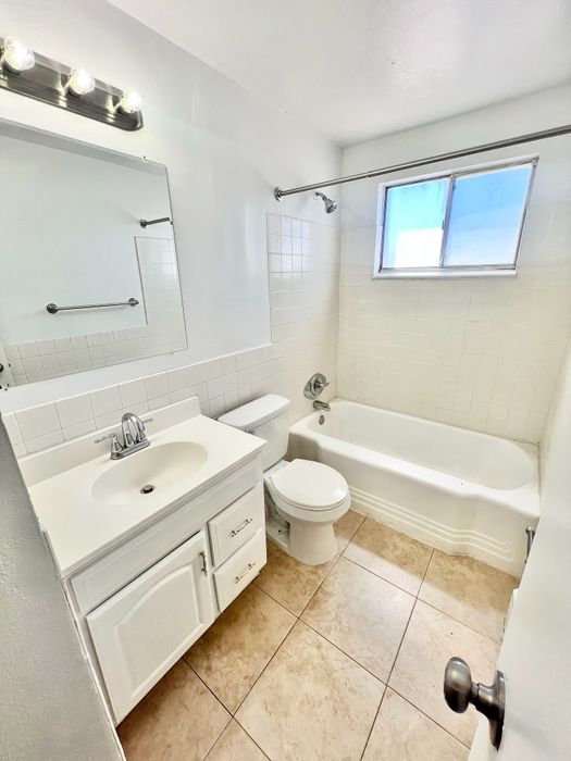 Bright and inviting bathroom featuring a sleek bathtub, modern vanity, and natural light from the window.