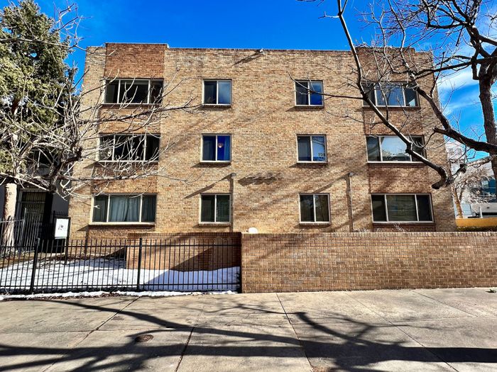 Charming three-story brick apartment building with large windows and a secure gated entrance, offering a welcoming and safe living environment.
