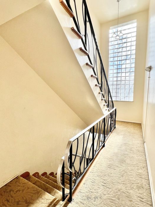 Elegant staircase with artistic railing and large window, offering abundant natural light in a modern home.