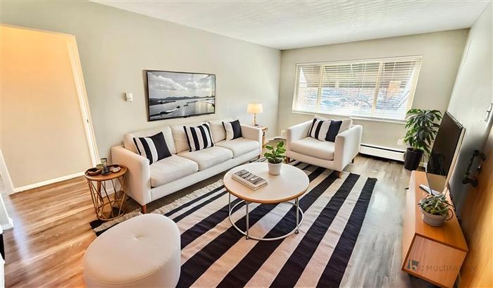 Inviting living room with sleek modern furniture, natural light, and stylish decor, perfect for relaxation and entertainment.