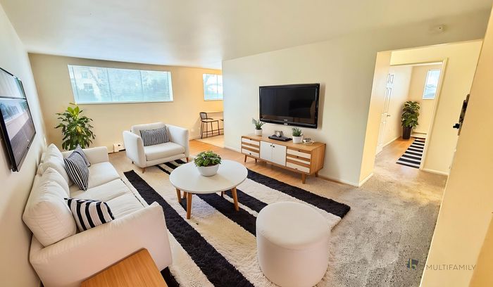 Modern living room with elegant white furniture, striped accents, large windows, and contemporary decor.