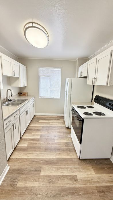 Bright kitchen with modern white cabinets, sleek appliances, and wood-style flooring, perfect for culinary creativity.