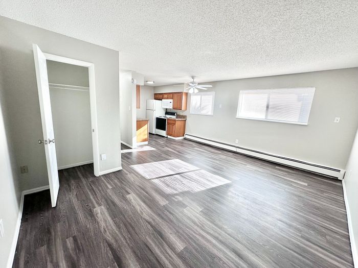 Chic and spacious open-plan apartment with elegant dark wood flooring, modern kitchen, and abundant natural light.