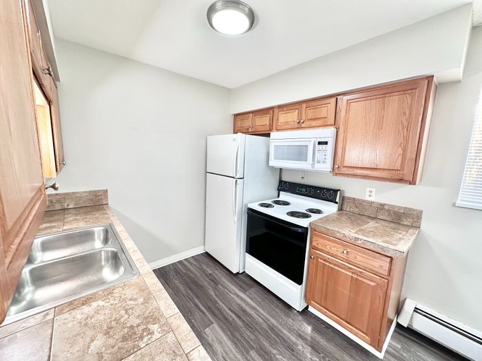 Modern kitchen with elegant wooden cabinets, tile countertops, and essential appliances for a cozy cooking experience.