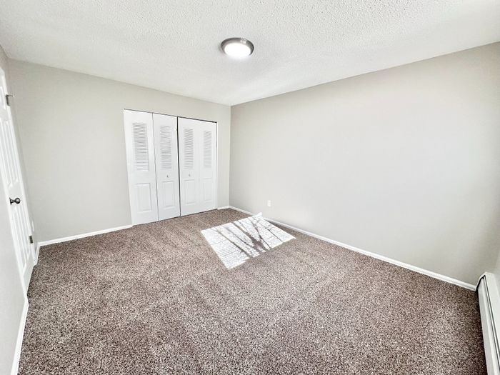 Bright and spacious bedroom with plush carpeting and ample closet space, perfect for a cozy retreat.