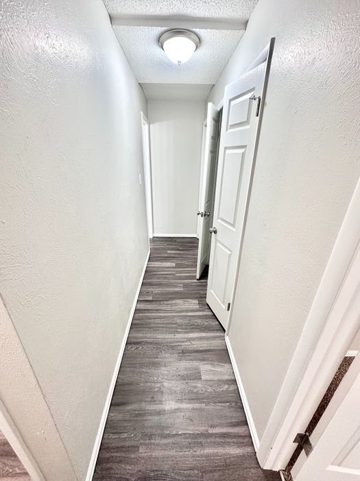 Bright, modern hallway with sleek laminate flooring and crisp white doors, offering a welcoming entryway.