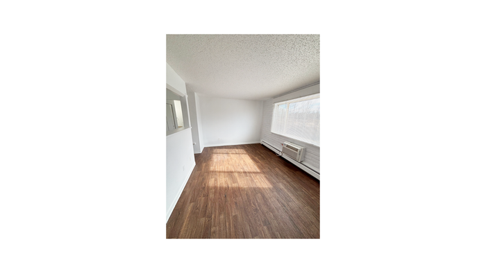 Bright, open living space with elegant wood flooring and large windows providing abundant natural light.