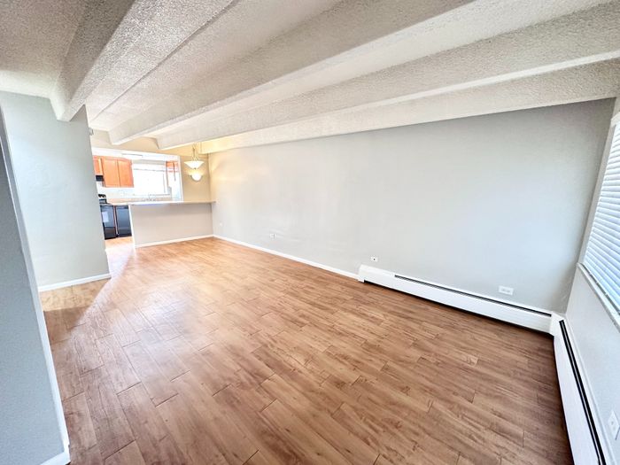 Bright, open-concept living space with elegant wood flooring and modern kitchen access, perfect for entertaining.
