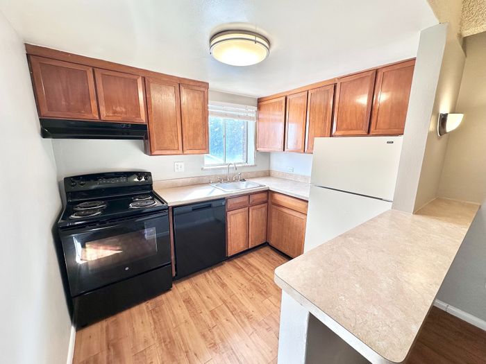Charming kitchen with warm wooden cabinets, sleek black appliances, and a bright, airy ambiance.