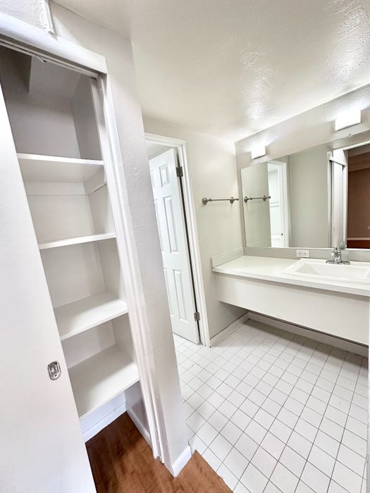 Bright and spacious bathroom with modern white tiles, generous shelving, and elegant fixtures.