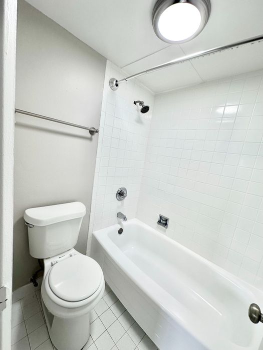 Elegant and modern bathroom featuring a pristine white bathtub, sleek fixtures, and contemporary lighting.