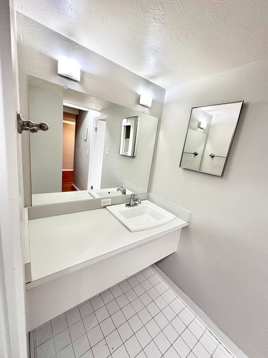 Modern bathroom vanity featuring a sleek rectangular sink, large mirror, and elegant wall lighting, perfect for a contemporary apartment.