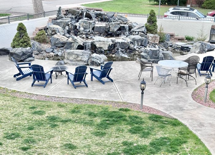 Charming outdoor patio with cozy Adirondack chairs and a stunning rock waterfall feature, perfect for relaxation and gatherings.