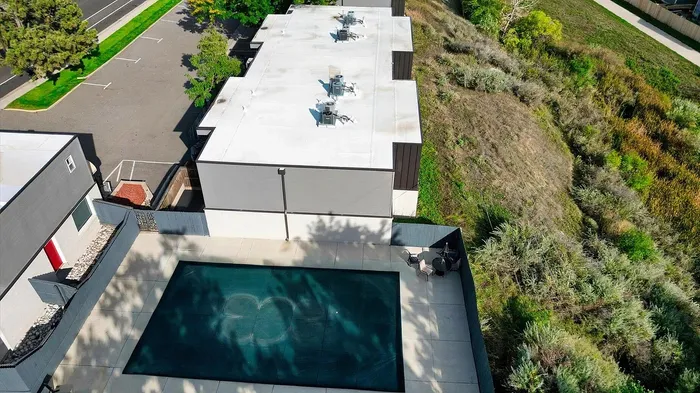 Aerial view of modern apartment complex featuring lush greenery and a sleek swimming pool area.