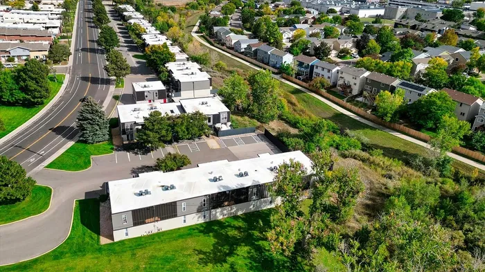 Aerial view of a charming residential community surrounded by lush greenery and well-maintained roads, ideal for a tranquil lifestyle.