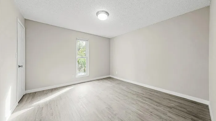 Bright, spacious living area with elegant hardwood floors and large sliding glass doors leading to a private patio.