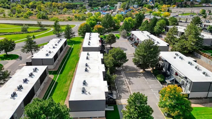 Aerial view of modern apartment complex surrounded by lush greenery and scenic pathways, ideal for tranquil living.