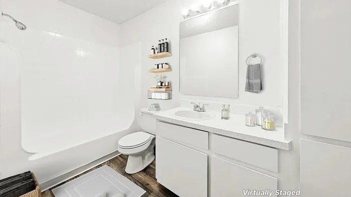 Virtually staged modern bathroom showcasing a pristine white bathtub, sleek vanity with ample counter space, and elegant shelving for toiletries. Warm wood flooring adds a touch of sophistication.