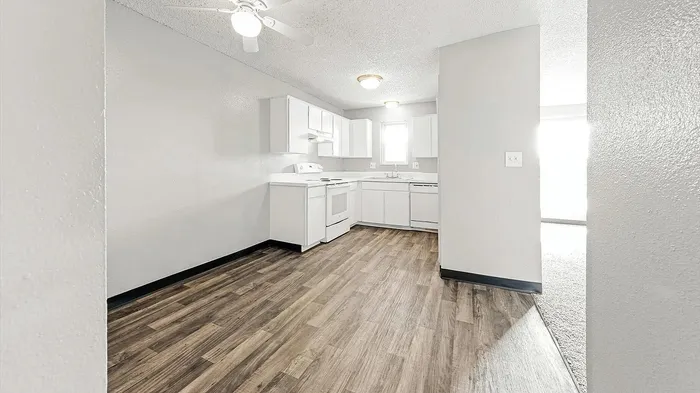 Bright and modern white kitchen with sleek cabinetry and elegant wood flooring.