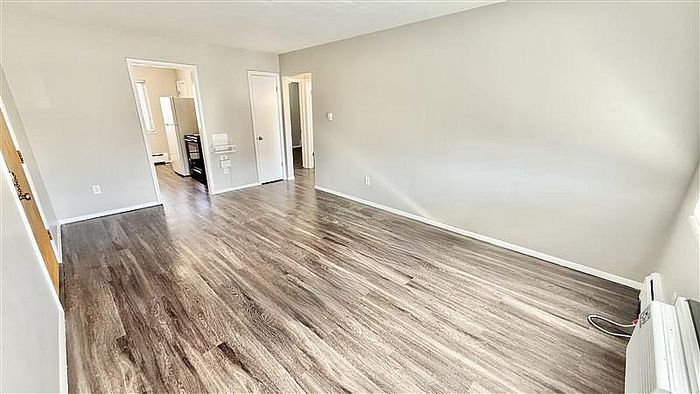Bright, spacious living area with sleek wooden floors and ample natural light, creating an inviting atmosphere.