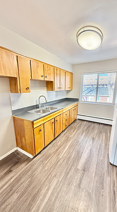 Bright kitchen with wooden cabinets, modern flooring, and large window, perfect for culinary adventures.