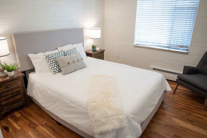 Cozy and stylish bedroom with a plush bed, elegant wood floors, and ample natural light creating a serene atmosphere.