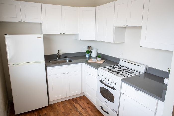 Bright and modern kitchen with sleek white cabinets, stylish gray countertops, and rich hardwood floors.