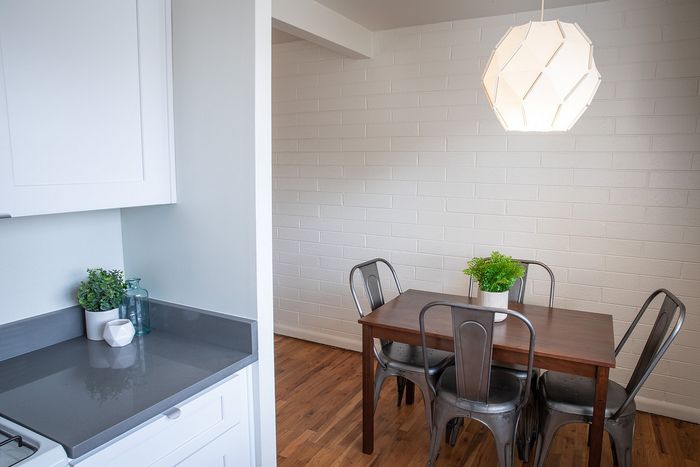 Chic dining area with modern metal chairs and a stylish light fixture adjacent to a sleek kitchen counter.