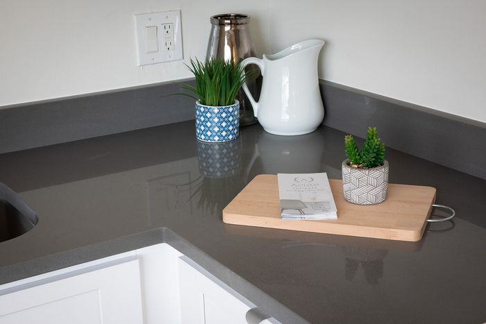 Modern kitchen countertop with sleek gray surface, stylish potted plants, and elegant decor, creating an inviting and contemporary space.