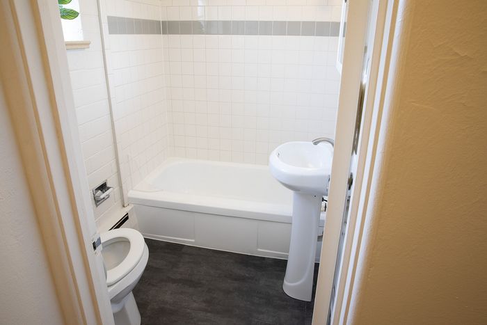 Bright and modern bathroom featuring elegant white tiles, a sleek pedestal sink, and a luxurious soaking tub.