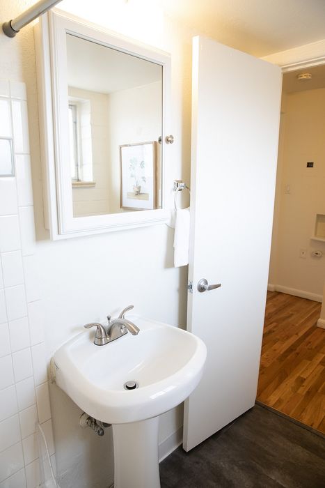 Bright and modern bathroom with sleek pedestal sink, elegant mirror, and contemporary fixtures.