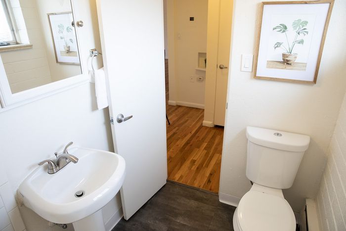 Bright and modern bathroom featuring a sleek white sink, contemporary fixtures, and a stylish artwork accent.