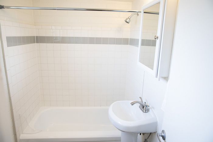Bright bathroom with modern white tiles, elegant sink, and sleek showerhead.